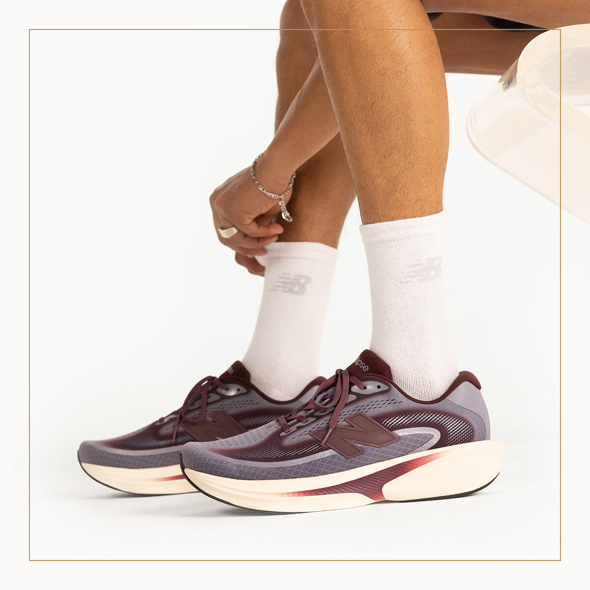 A man pulling up his socks while wearing New Balance Ellipse sneakers. 